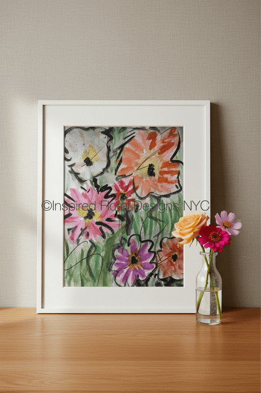 A framed floral art print by Barbara at Inspired Floral Designs NYC leaning against a beige wall on a wooden surface, with a small glass vase of flowers beside it. The artwork shows colorful flowers in pink, orange, purple, white, and green. Copyright