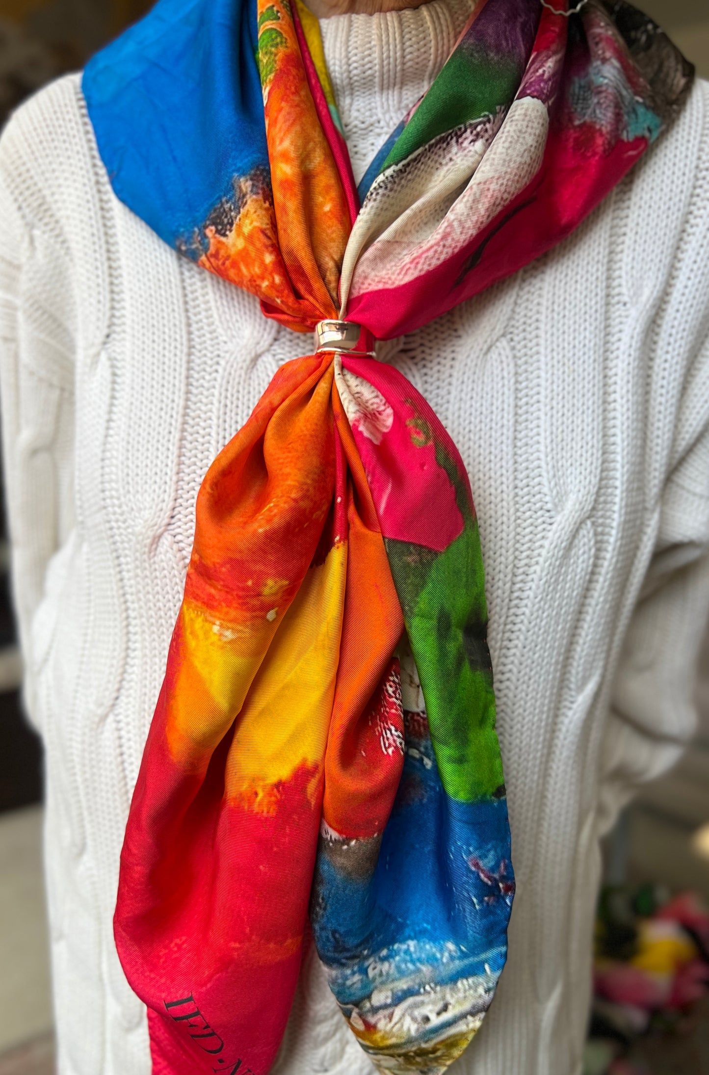 Colorful silk scarf titled fragmented blossoms at inspired floral designs nyc tied around a person's neck with a white sweater