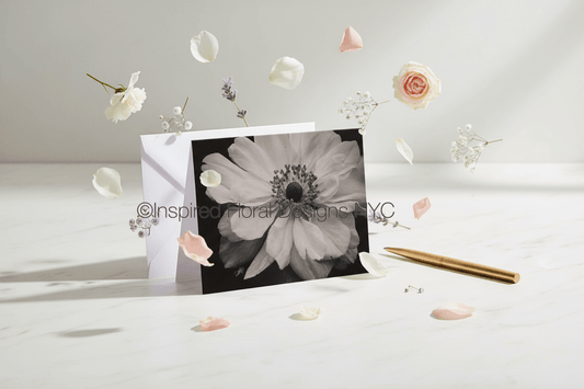 Floral card with a black and white flower design by Whitney on a light surface with scattered flowers by inspired floral designs nyc copyright.