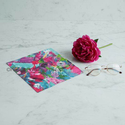 Floral cleaning cloth, pink flower, and glasses on a marble surface