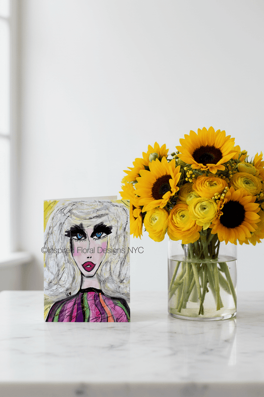 Vase of sunflowers on a marble surface with a greeting card of stylized face by inspired floral designs nyc in the background