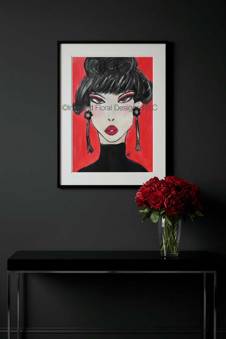 Framed artwork of a stylized face with red background on a black wall above a black console table with a vase of red roses by Inspired Floral Designs NYC LLC Copyright