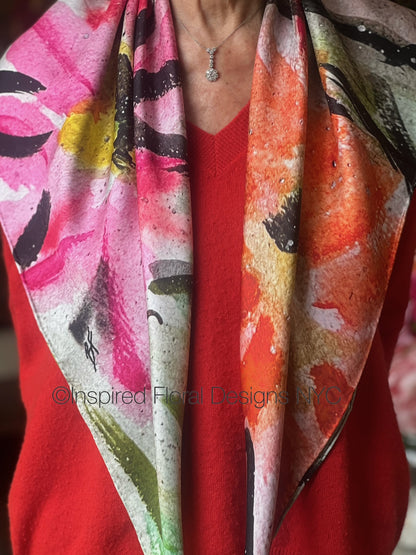 Colorful floral-patterned scarf titled peace in the edit floral art in silk collection for inspired floral designs nyc draped over a person wearing a red garment copyright