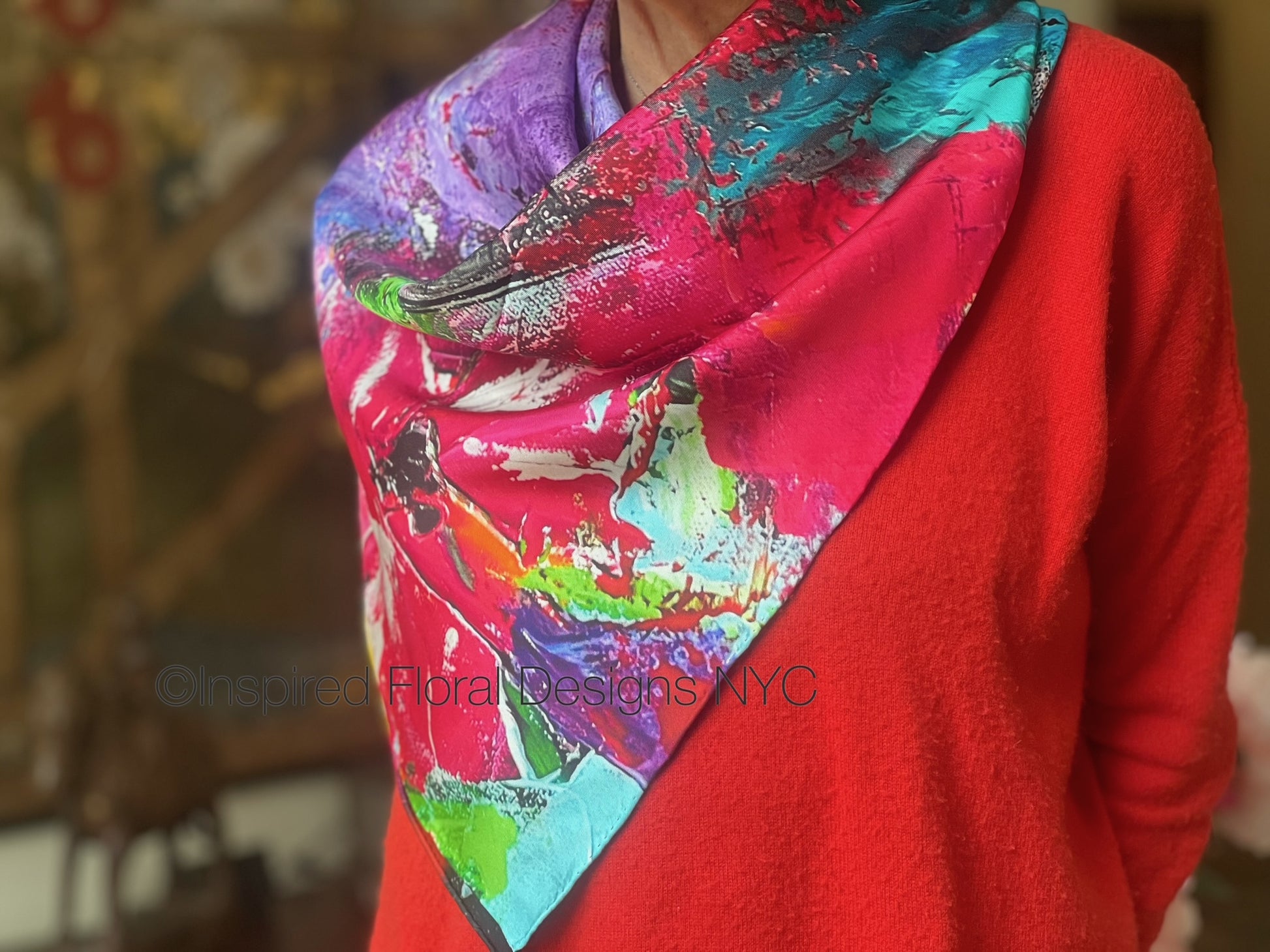 Person wearing a colorful floral abstract scarf titled petals in the wild by inspired floral designs nyc brand on a blurred background copyright