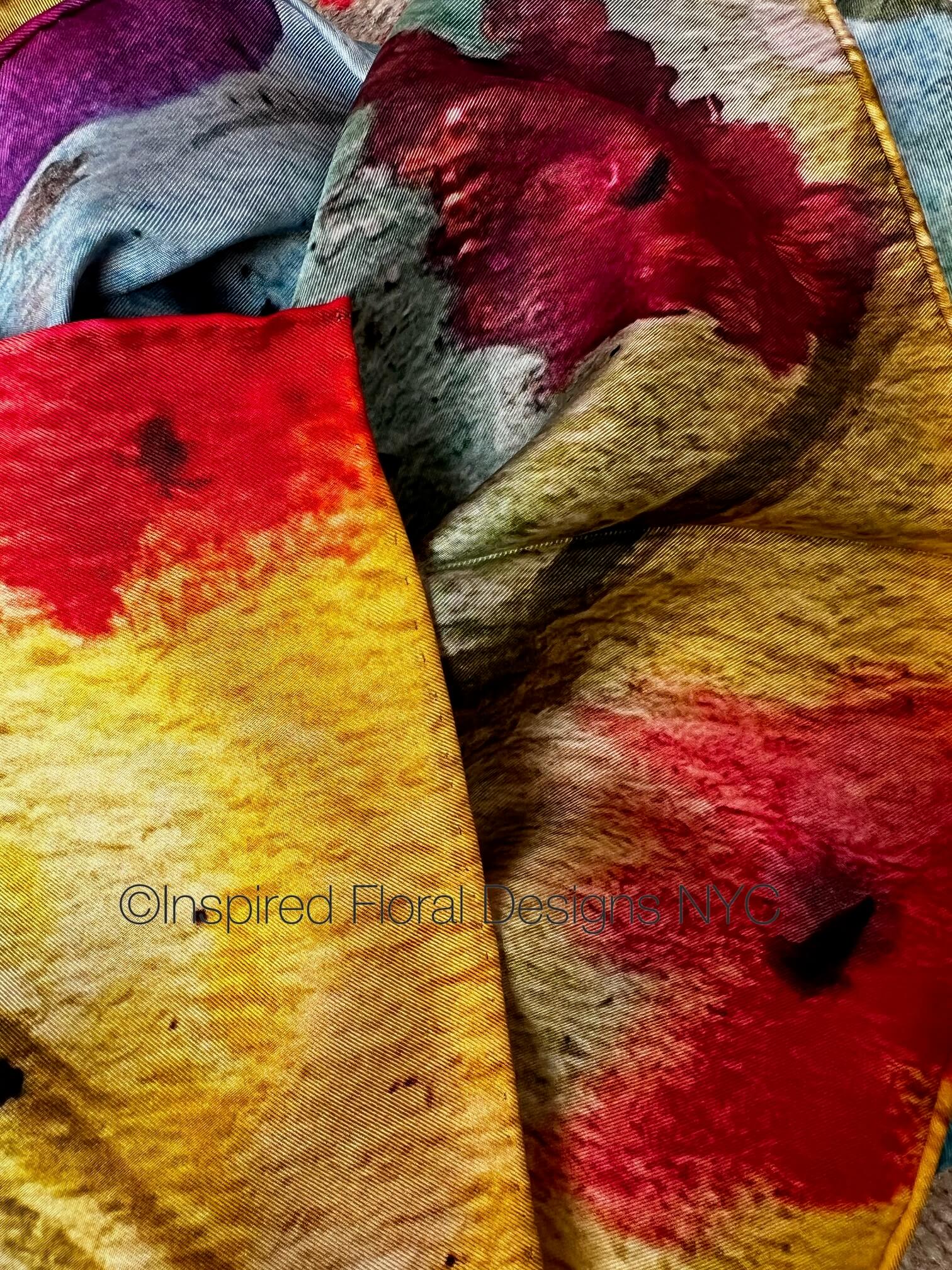Close-up of textured fabric with red and yellow floral patterns on a scarf by inspired floral designs nyc titled floral symphony copyright 
