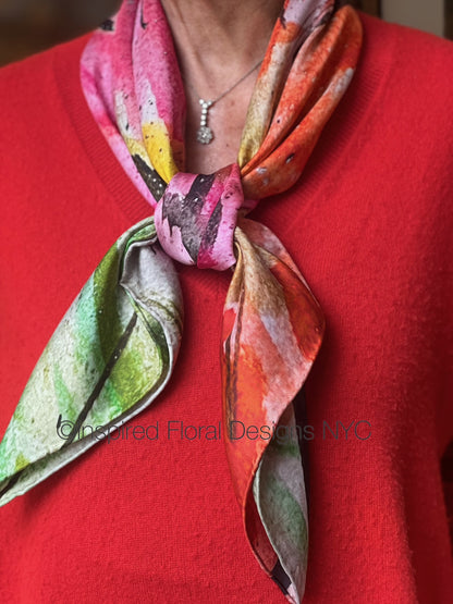 Person wearing a colorful scarf titled Peace from The Edit: Floral art in silk collection with a red background copyright inspired floral designs nyc 