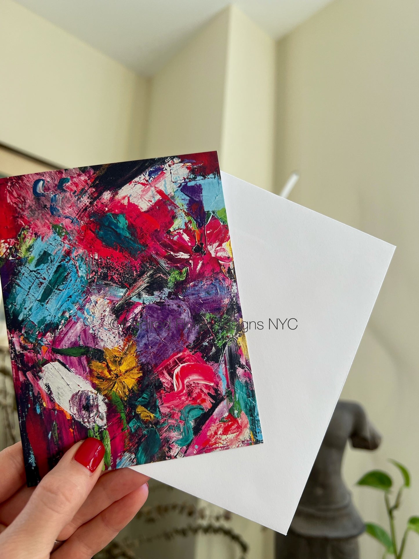 Colorful abstract floral petals in the wild greeting card by inspired floral designs nyc held by a hand with red nail polish, against a neutral background copyright