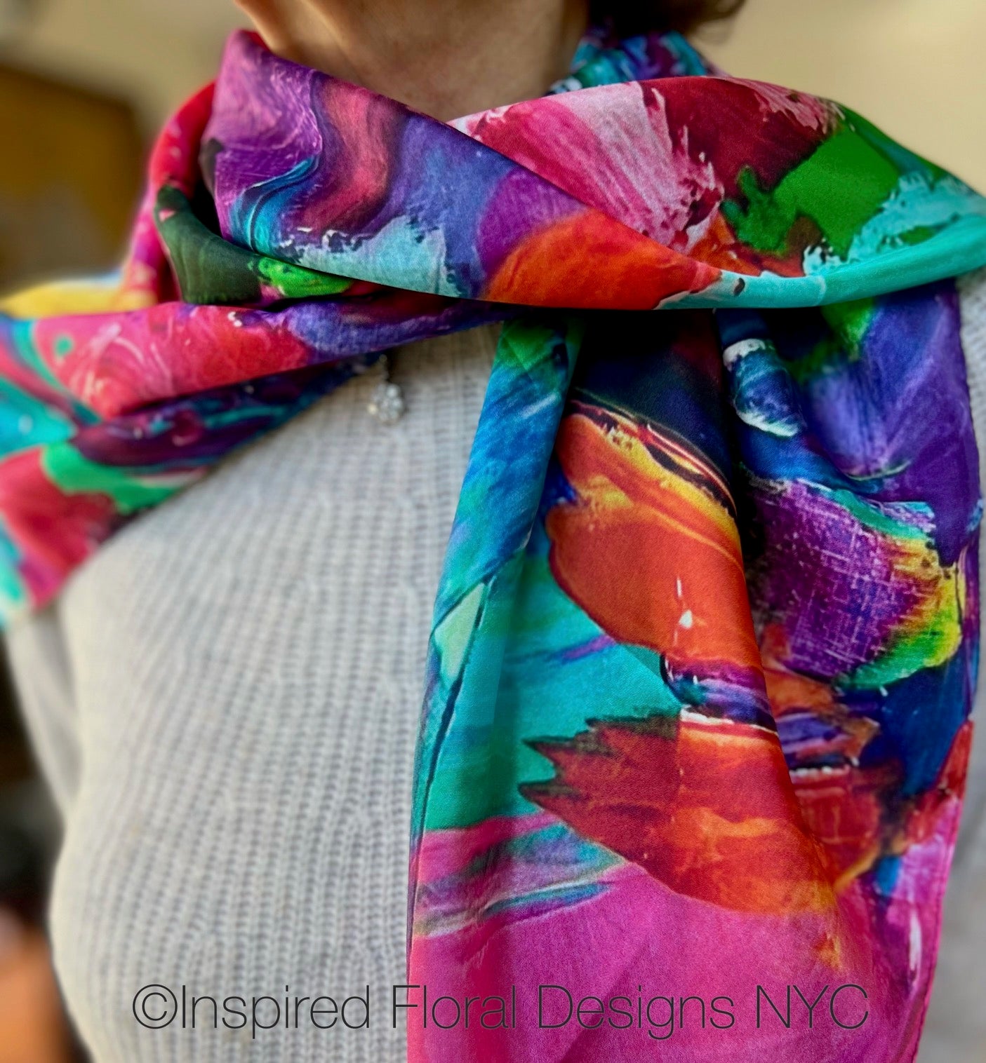 Colorful scarf with abstract floral design worn by a person, featuring the brand Inspired Floral Designs NYC titled petals unleashed copyright