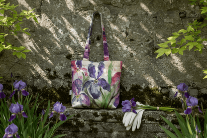 Floral-patterned handbag on a stone ledge with purple flowers and gardening gloves. Inspired floral Designs nyc 