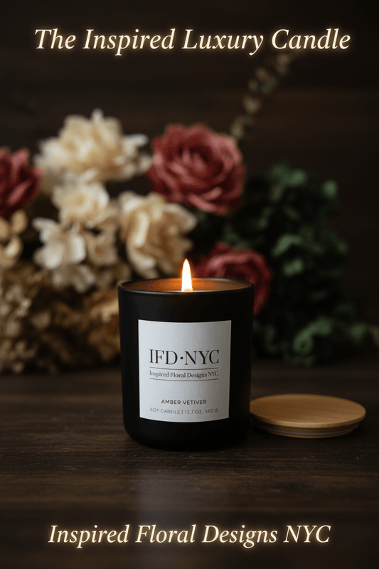 Luxury candle with 'IFD NYC' label in front of flowers on a dark background