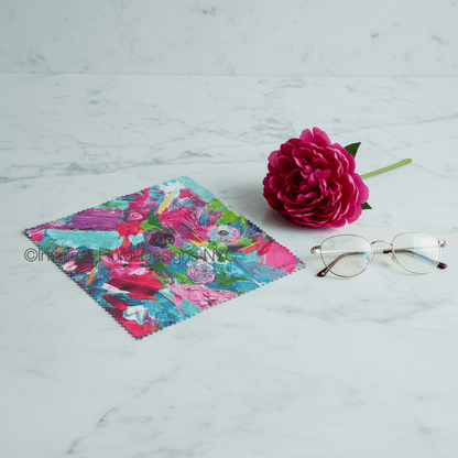 Floral cleaning cloth, pink flower, and glasses on a marble surface