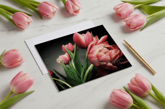 Card with pink tulips surrounded by real tulips on a white surface inspired floral designs nyc