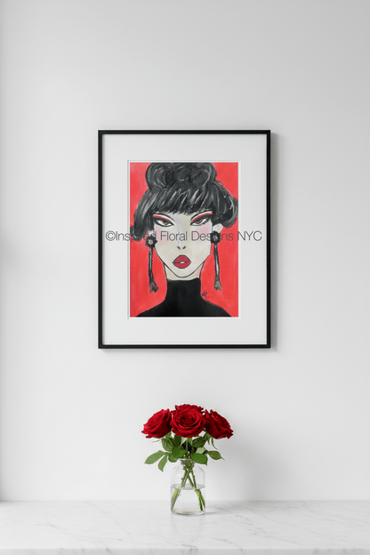 Framed artwork of a stylized face with red background on a white wall, next to a vase of red roses by Inspired Floral Designs NYC LLC copyright